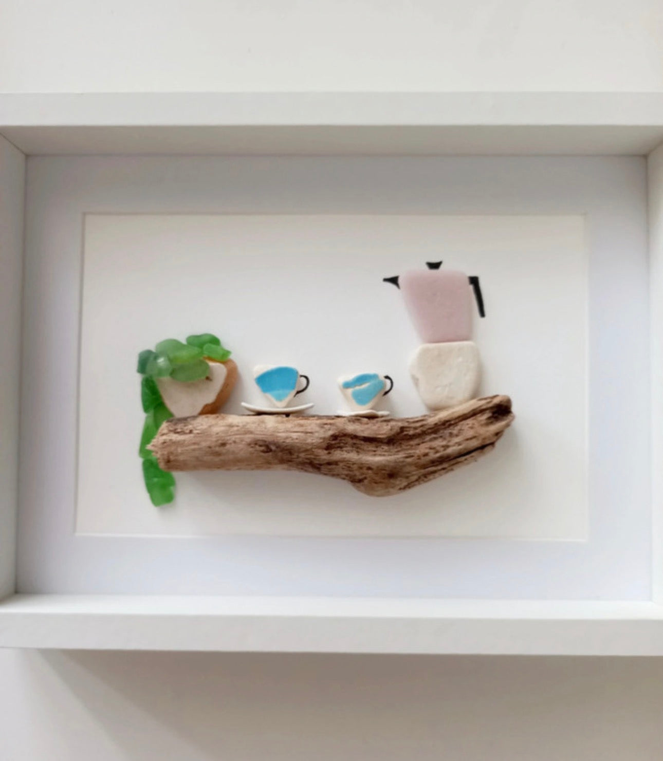 Quadro realizzato a mano con vetri di mare raffigurante una caffettiera e tazzine su un legno di mare, stile minimalista per arredamento casa.